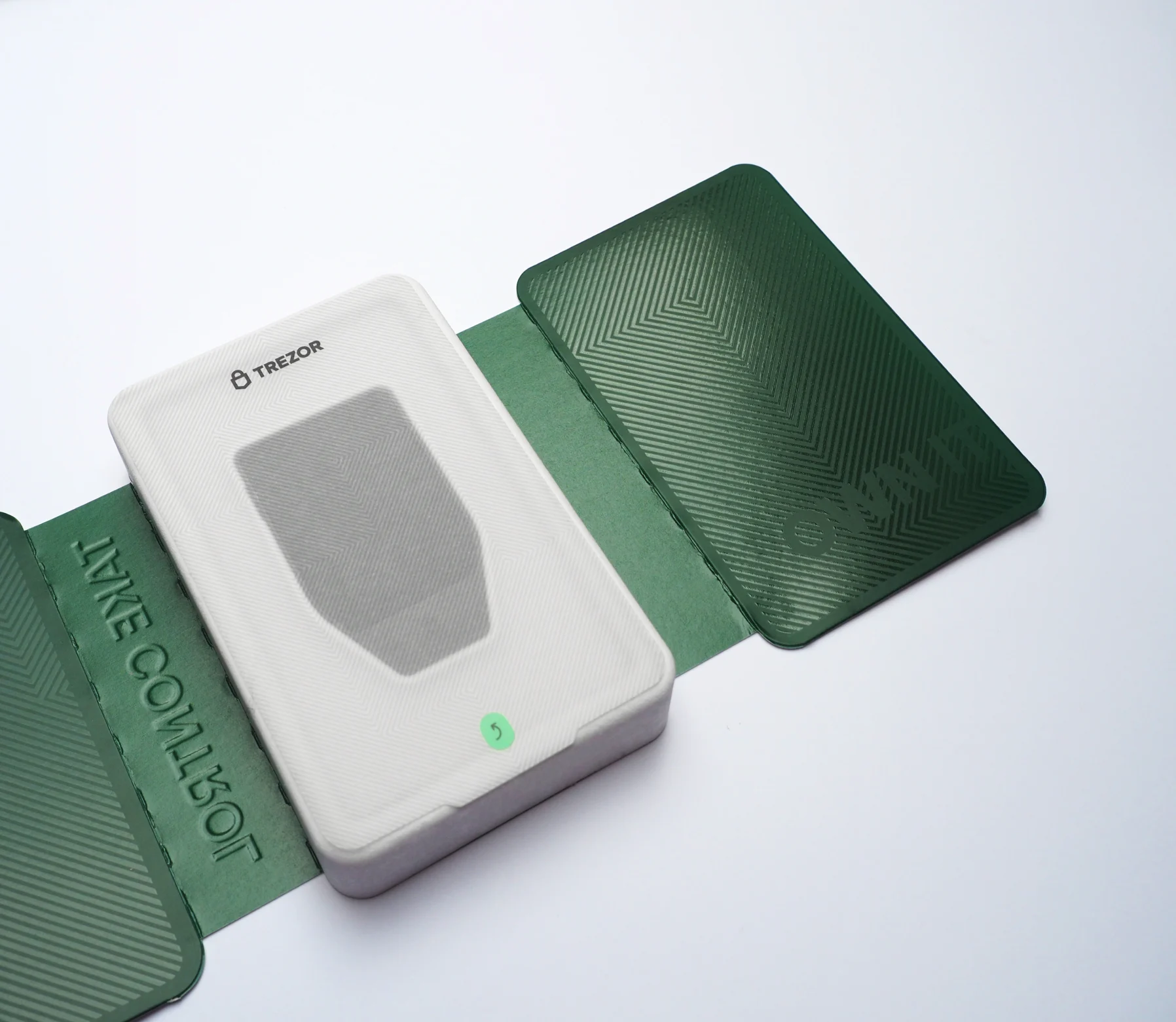 The green outer sleeve unfolded flat — a white device tray between embossed panels reading “Take control” and “Own it”.