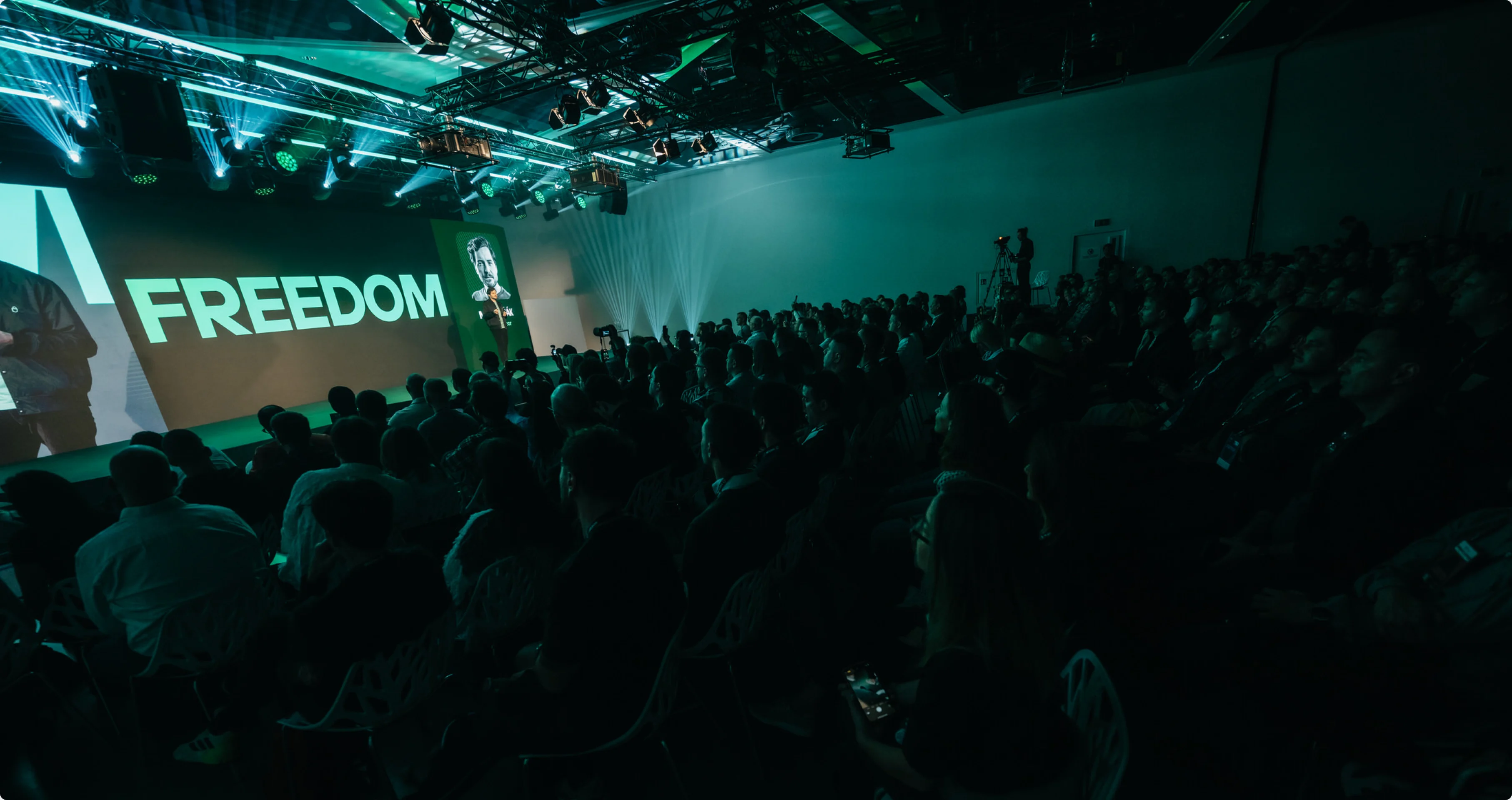 The launch keynote — “Freedom” on a green-lit screen above a packed audience.