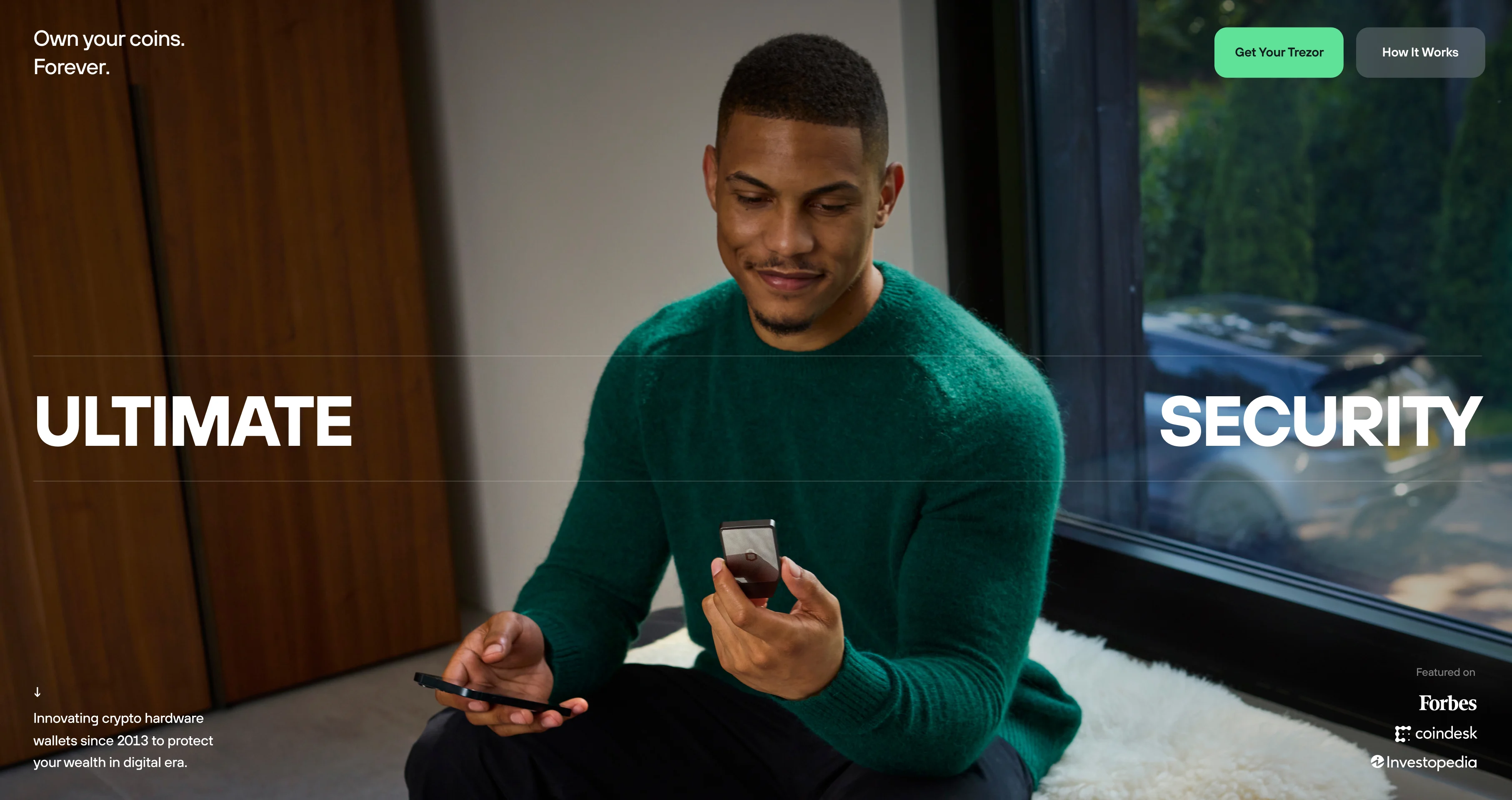 The e-shop hero — a man on a couch with his phone, “Own your coins. Forever.” and “Ultimate security”.